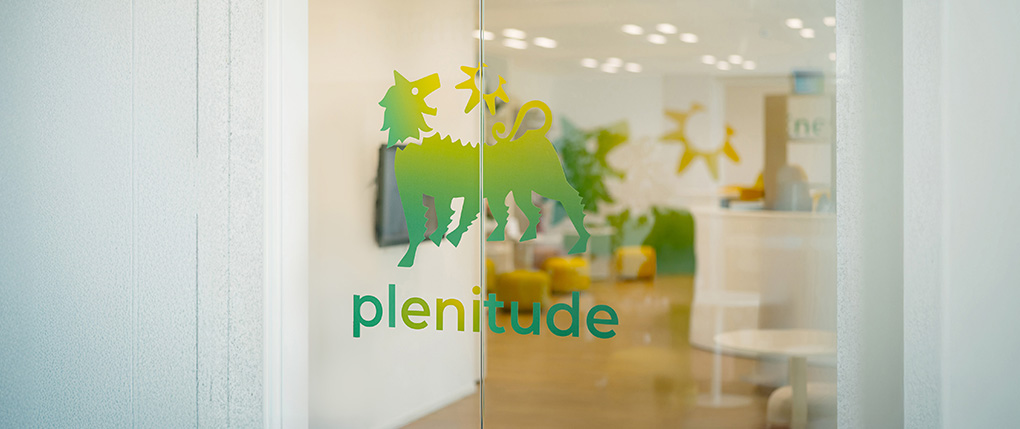A glass door with the word Plenitude and the company logo. Beyond the glass door is an office.